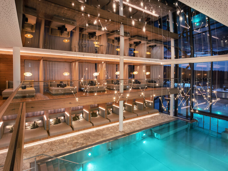 Der modern gestaltete Innenpool des Tonihof im Bayerischen Wald wird von gemütlichen Liegen umrahmt und bietet durch ein großes Fenster direkten Zugang zum Außenbereich.